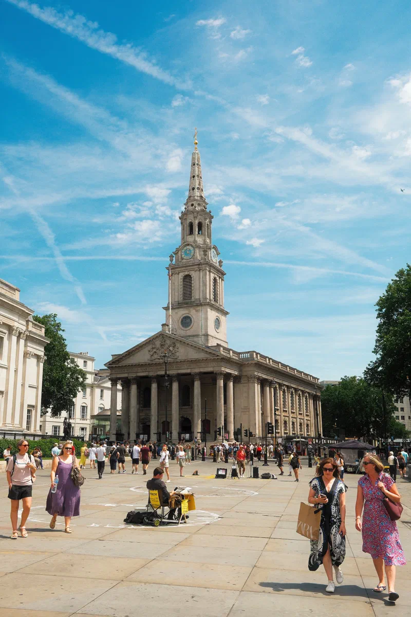 St Martin-in-the-Fields across Trafalgar Square, with a busker at work.